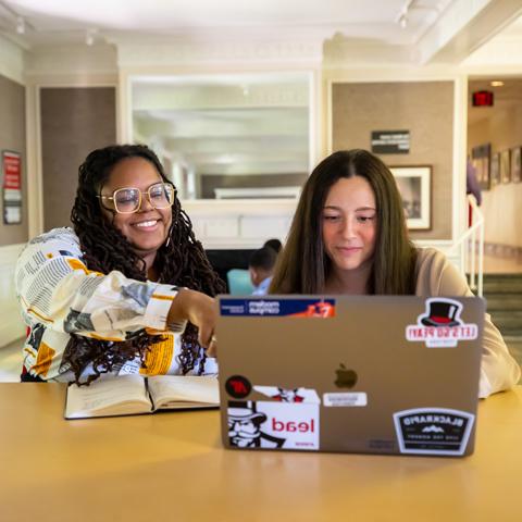 two students working at a laptop